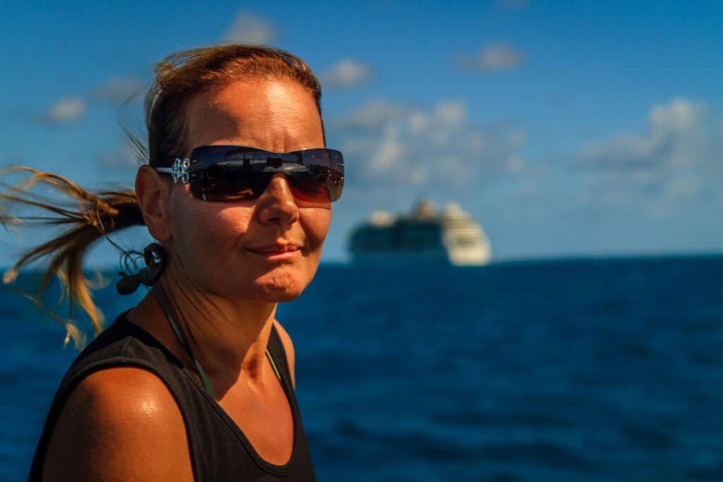 Frau auf See vor Kreuzfahrtschiff im Hintergrund